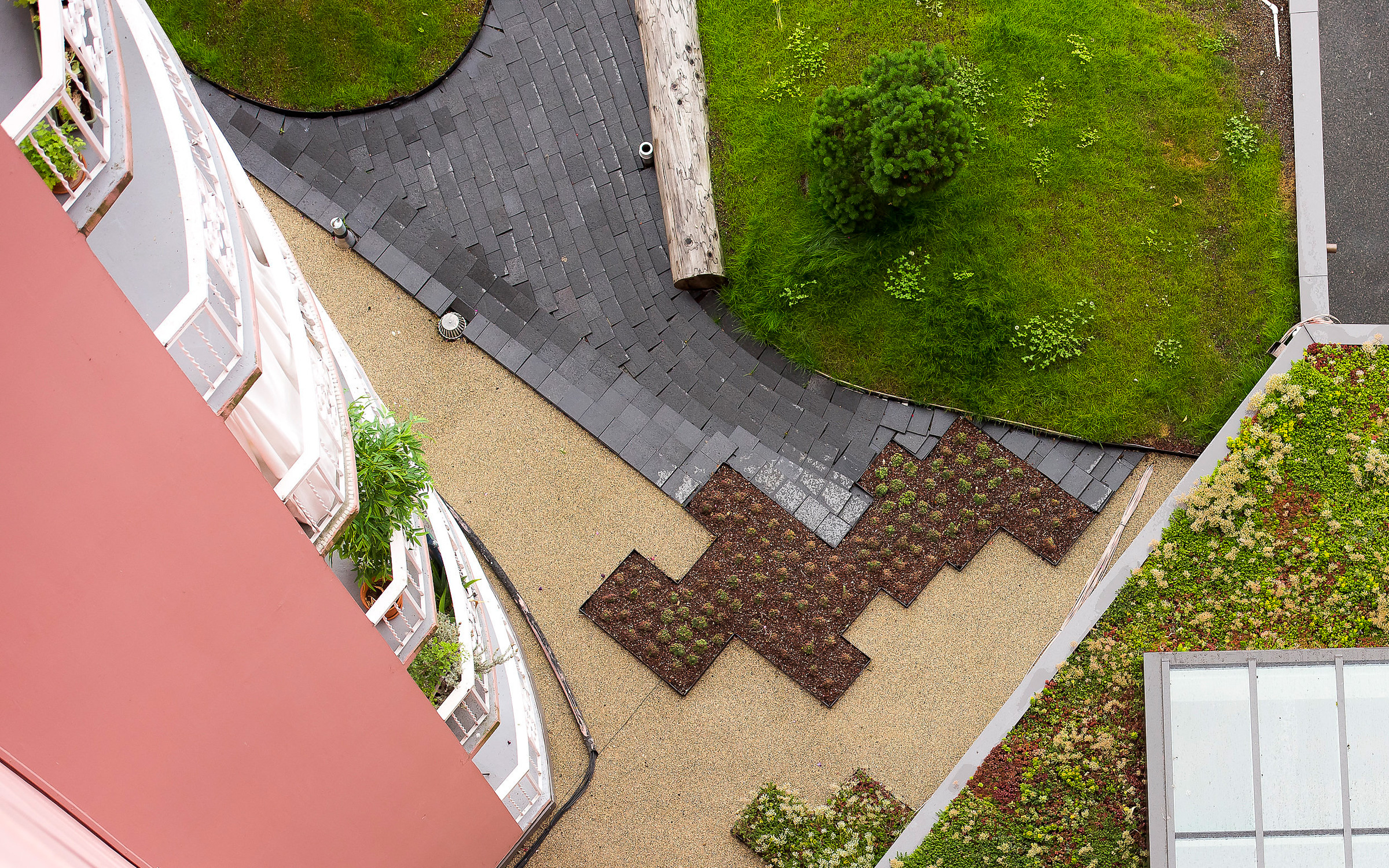 The residents can let their eyes wander across a sophisticated roof landscape. Bird's eye view onto areas vegetated with Sedum, lawn and walkways
